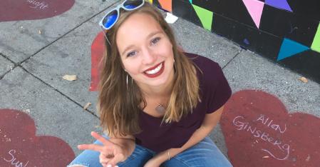 Program Costs & What’s Included au pair sitting on the ground smiling into the camera