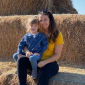 au pair with host kid sitting on hay bales